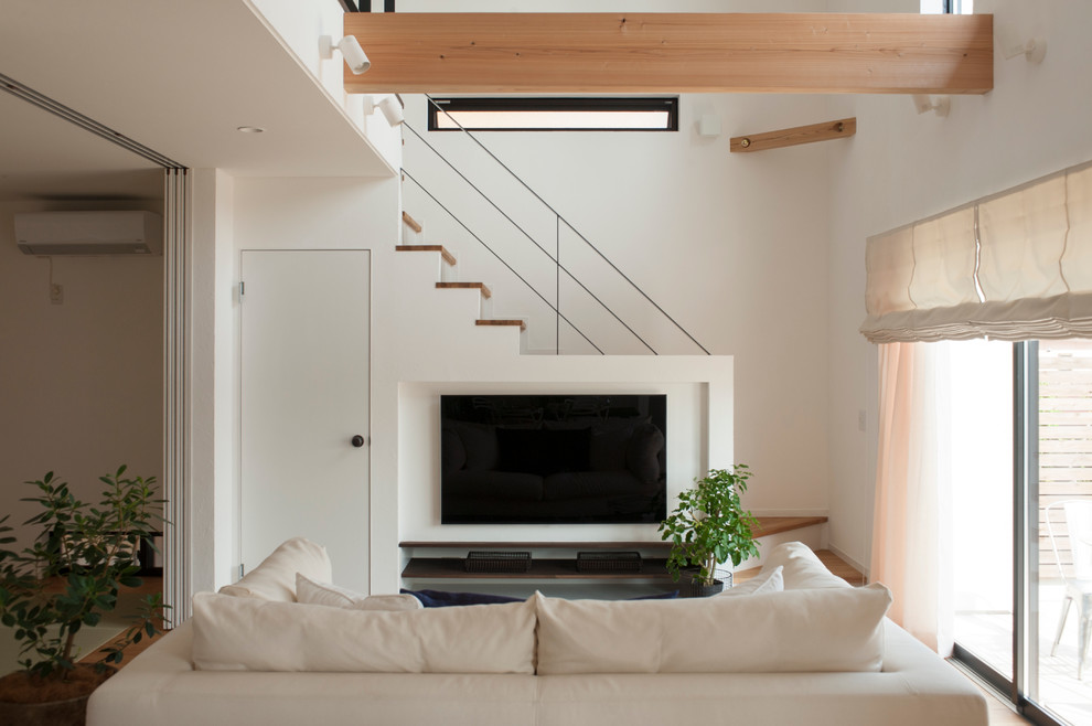 Idéer för ett skandinaviskt vardagsrum, med vita väggar, mellanmörkt trägolv, en väggmonterad TV och brunt golv