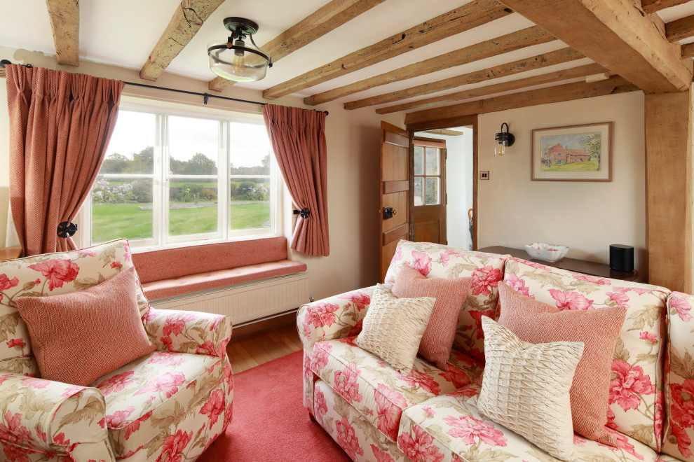 Modelo de salón cerrado campestre con paredes beige, suelo de madera en tonos medios, suelo marrón y vigas vistas