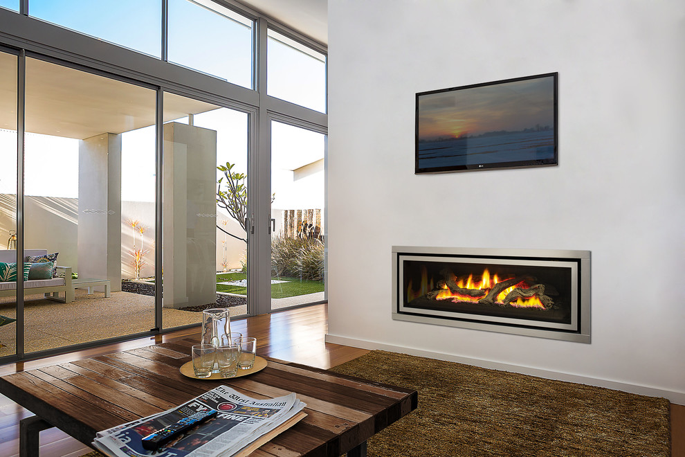 Photo of a large modern open plan living room in Melbourne with white walls, medium hardwood flooring, a ribbon fireplace, a metal fireplace surround and a wall mounted tv.