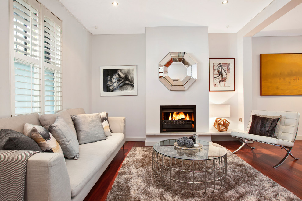 Idée de décoration pour un petit salon minimaliste ouvert avec un mur blanc, un sol en bois brun, une cheminée standard, un manteau de cheminée en métal, un sol marron et un plafond décaissé.