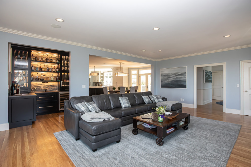 Modern inredning av ett stort separat vardagsrum, med en hemmabar, grå väggar, mellanmörkt trägolv, en standard öppen spis, en väggmonterad TV och brunt golv