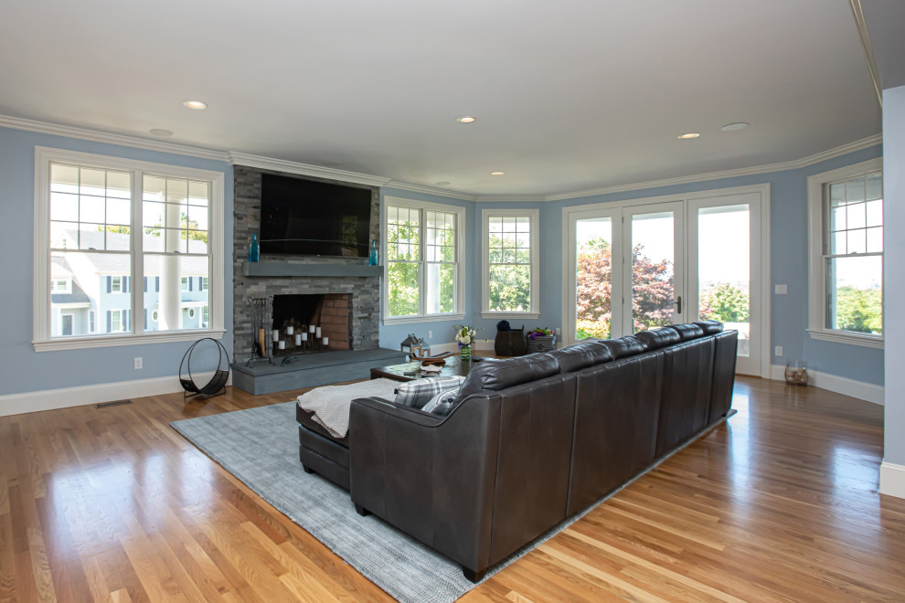Großes, Abgetrenntes Modernes Wohnzimmer mit Hausbar, grauer Wandfarbe, braunem Holzboden, Kamin, Kaminumrandung aus gestapelten Steinen, TV-Wand und braunem Boden in Boston