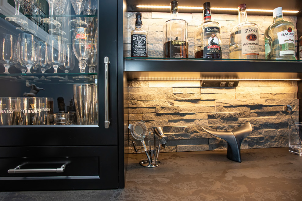 Diseño de salón con barra de bar cerrado moderno grande con paredes grises, suelo de madera en tonos medios, todas las chimeneas, piedra de revestimiento, televisor colgado en la pared y suelo marrón