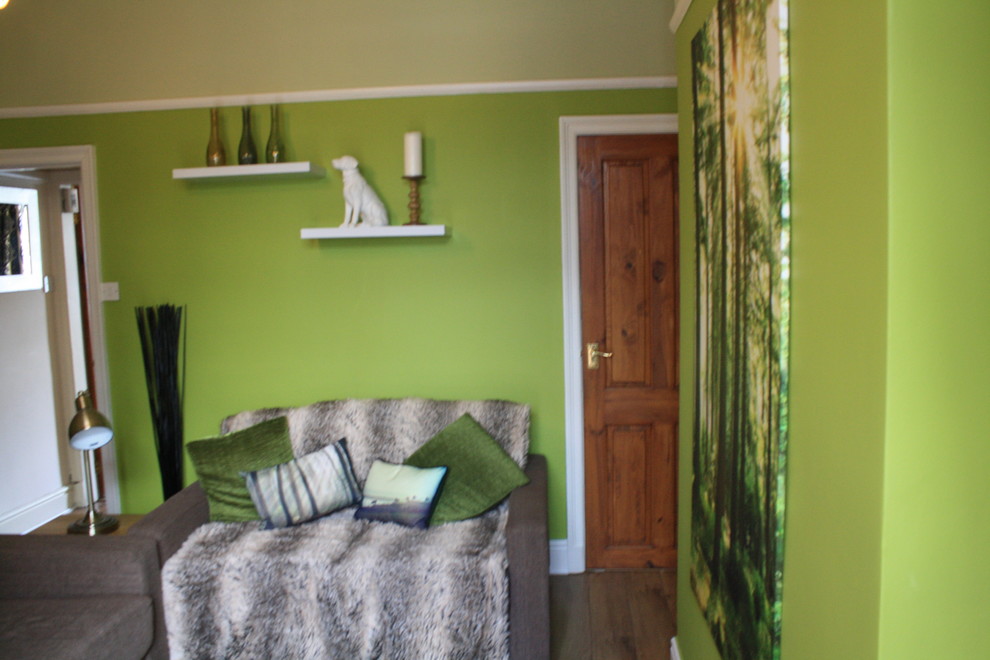 Bild på ett mellanstort funkis vardagsrum, med gröna väggar, laminatgolv och en fristående TV