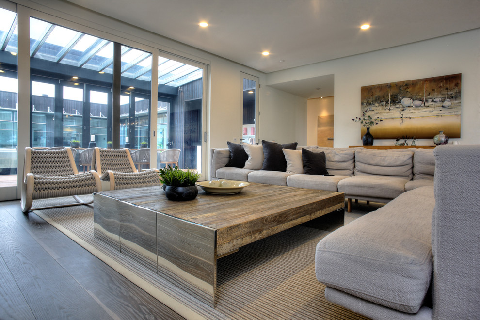 Example of a huge trendy open concept light wood floor living room design in Melbourne with white walls and a wall-mounted tv