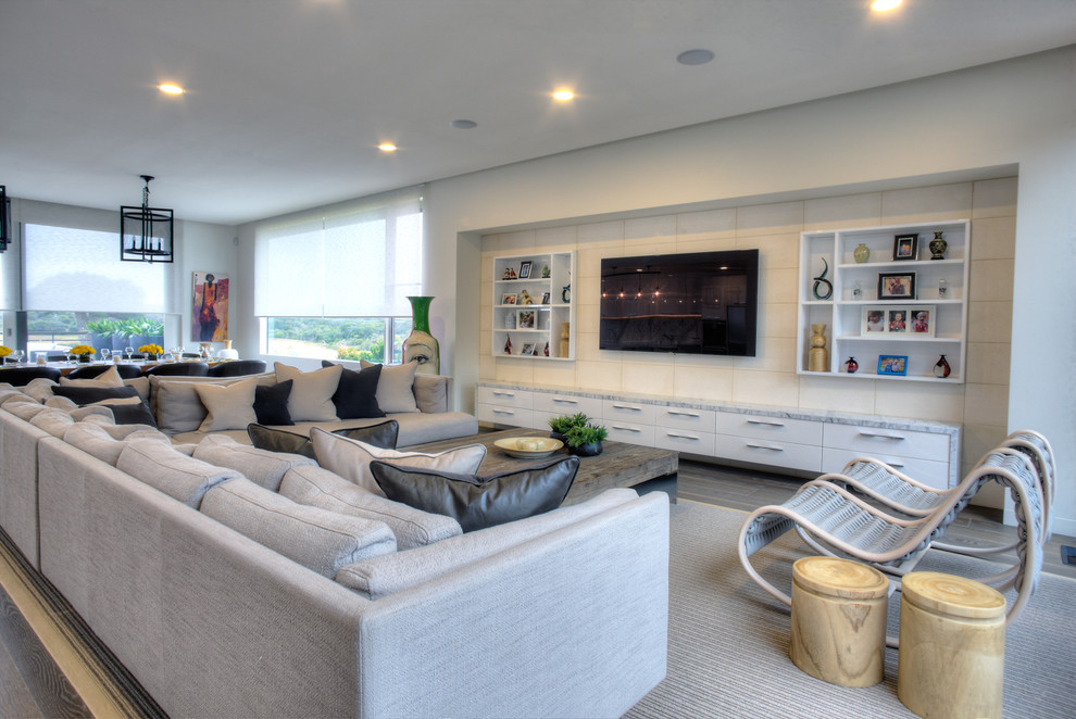 Cette image montre un très grand salon design ouvert avec un mur blanc, parquet clair et un téléviseur fixé au mur.