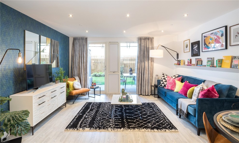 This is an example of a contemporary open plan living room in London with blue walls, light hardwood flooring, no fireplace, a freestanding tv and grey floors.