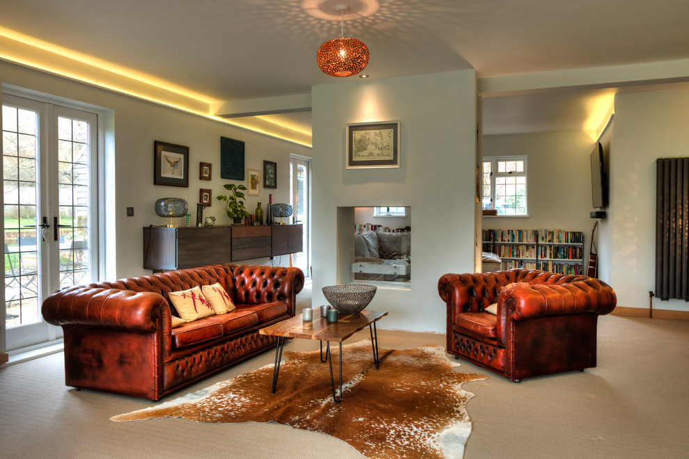 Exemple d'un grand salon éclectique ouvert avec un mur blanc, une cheminée double-face, un manteau de cheminée en plâtre, un téléviseur fixé au mur et un sol beige.