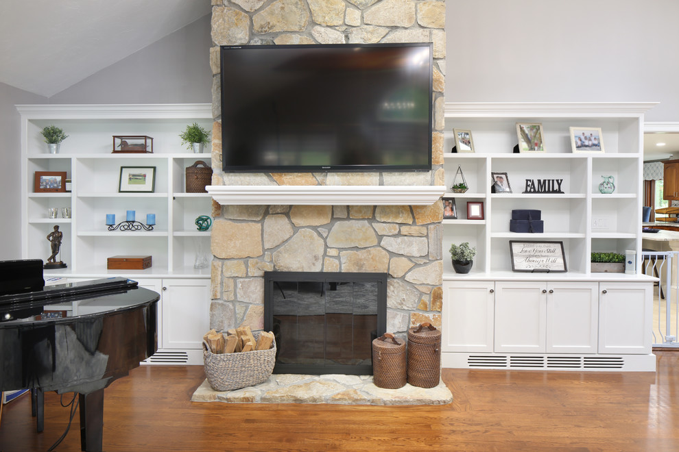Bild på ett stort vintage separat vardagsrum, med grå väggar, mellanmörkt trägolv, en standard öppen spis, en spiselkrans i sten, en väggmonterad TV och brunt golv