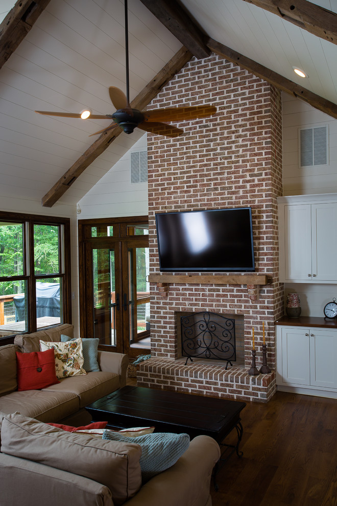 アトランタにある高級な中くらいなトラディショナルスタイルのおしゃれなリビング (白い壁、無垢フローリング、標準型暖炉、レンガの暖炉まわり、壁掛け型テレビ、茶色い床) の写真