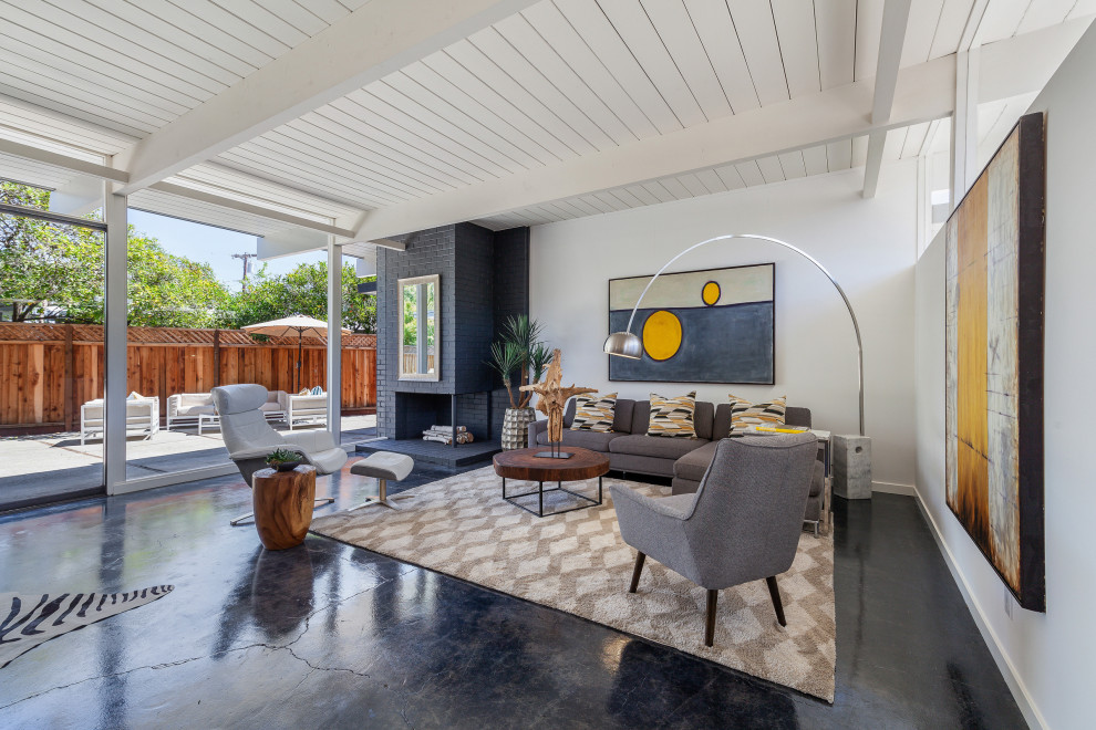 Inspiration for a 1960s concrete floor, black floor, exposed beam and shiplap ceiling living room remodel in San Francisco with white walls, a corner fireplace and a brick fireplace