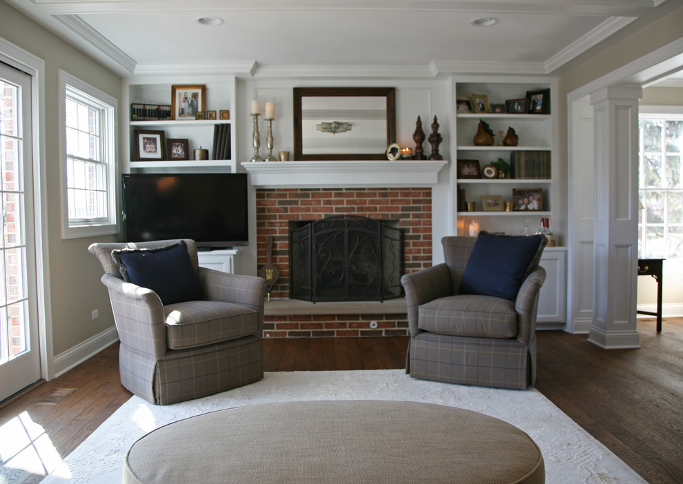 Inspiration for a mid-sized timeless enclosed medium tone wood floor living room remodel in Milwaukee with gray walls, a standard fireplace, a brick fireplace and a media wall