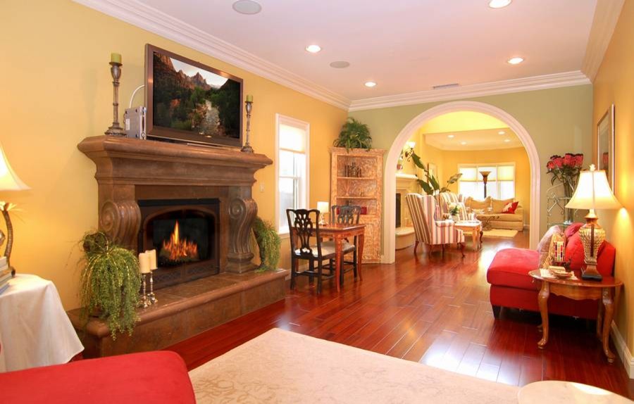 Example of a mid-sized transitional enclosed and formal medium tone wood floor and brown floor living room design in Los Angeles with beige walls, a standard fireplace, a stone fireplace and a tv stand