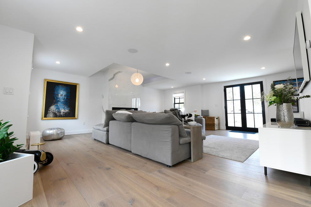 Cette photo montre un grand salon moderne ouvert avec un mur blanc, parquet clair, une cheminée standard, un manteau de cheminée en pierre et un plafond à caissons.