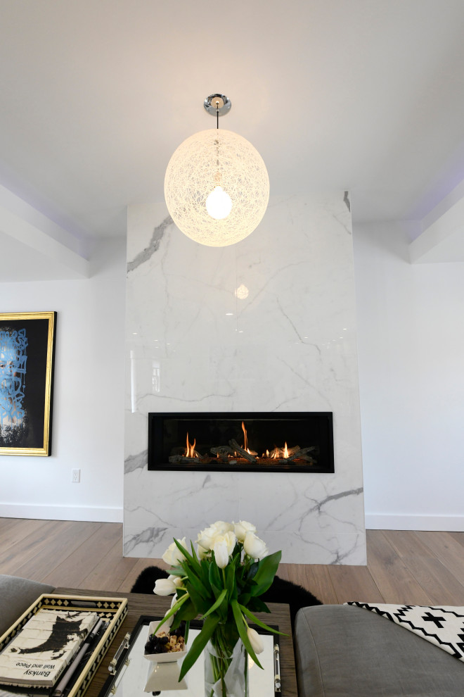 Esempio di un grande soggiorno minimalista aperto con pareti bianche, parquet chiaro, camino classico, cornice del camino in pietra e soffitto a cassettoni