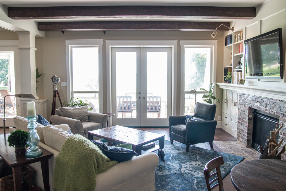 Пример оригинального дизайна: открытая гостиная комната среднего размера в стиле неоклассика (современная классика) с бежевыми стенами, темным паркетным полом, стандартным камином, фасадом камина из кирпича, телевизором на стене и коричневым полом