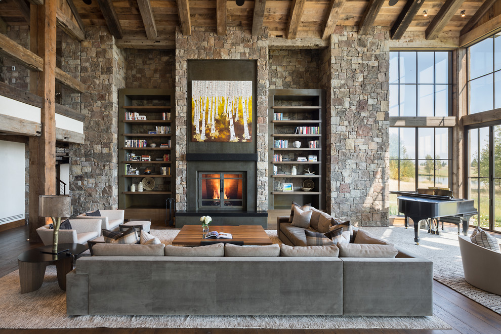 Diseño de biblioteca en casa abierta rústica sin televisor con suelo de madera oscura, todas las chimeneas, marco de chimenea de metal y piedra