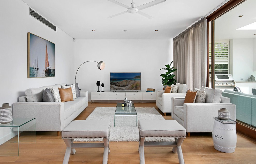 Стильный дизайн: открытая гостиная комната среднего размера в стиле неоклассика (современная классика) с белыми стенами, паркетным полом среднего тона, отдельно стоящим телевизором и коричневым полом - последний тренд