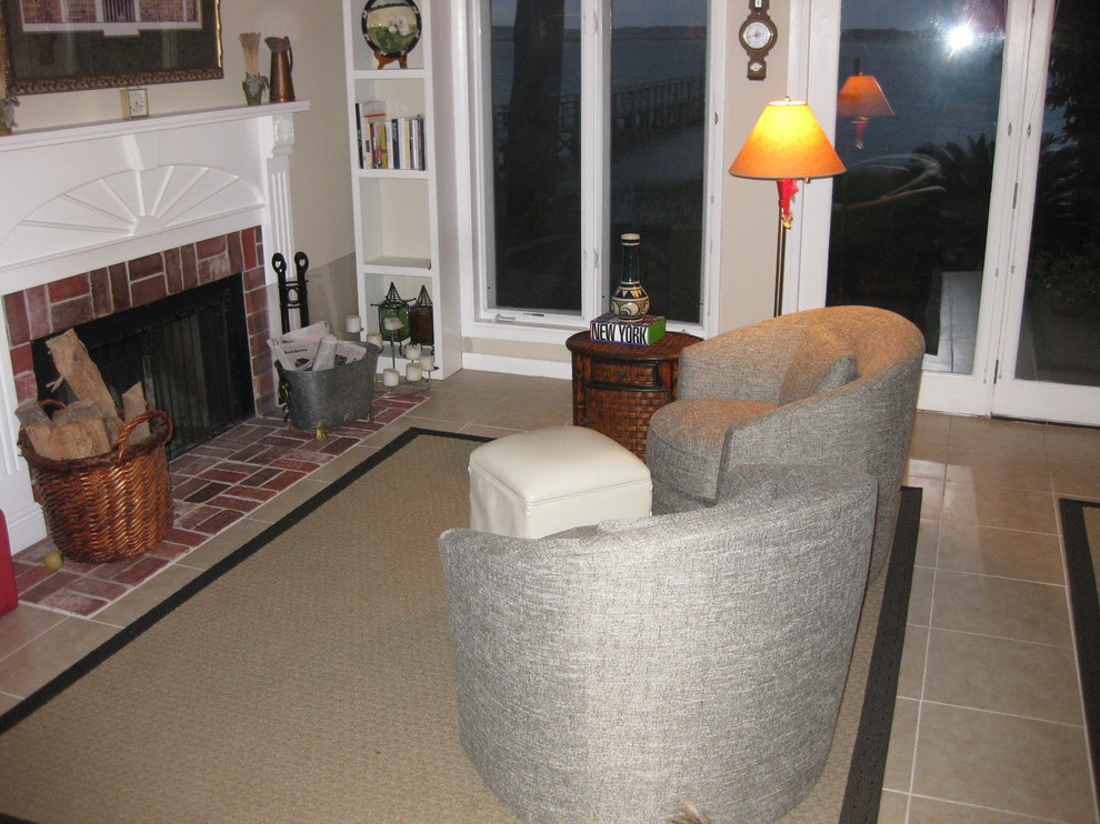 Esempio di un piccolo soggiorno chic aperto con pareti beige, pavimento con piastrelle in ceramica, camino classico, cornice del camino in mattoni e TV nascosta