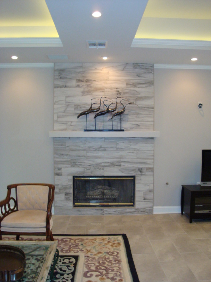 Пример оригинального дизайна: большая парадная, открытая гостиная комната в стиле неоклассика (современная классика) с серыми стенами, полом из керамической плитки, стандартным камином, фасадом камина из плитки и телевизором на стене