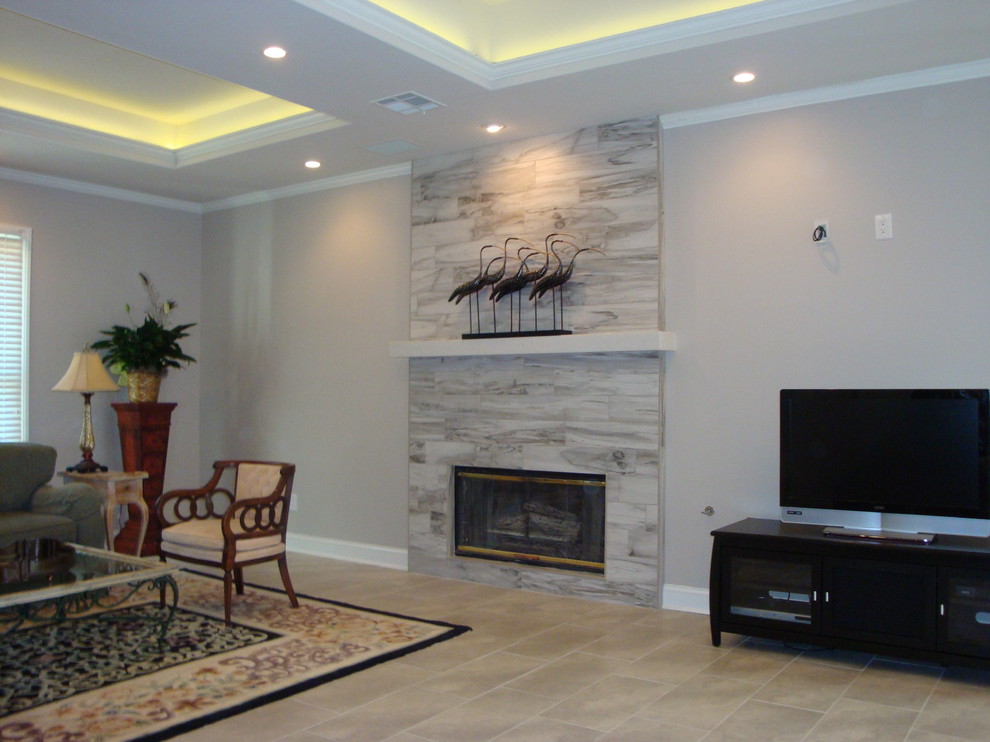 ジャクソンにあるラグジュアリーな広いトランジショナルスタイルのおしゃれなリビング (グレーの壁、セラミックタイルの床、標準型暖炉、タイルの暖炉まわり、壁掛け型テレビ、ベージュの床) の写真