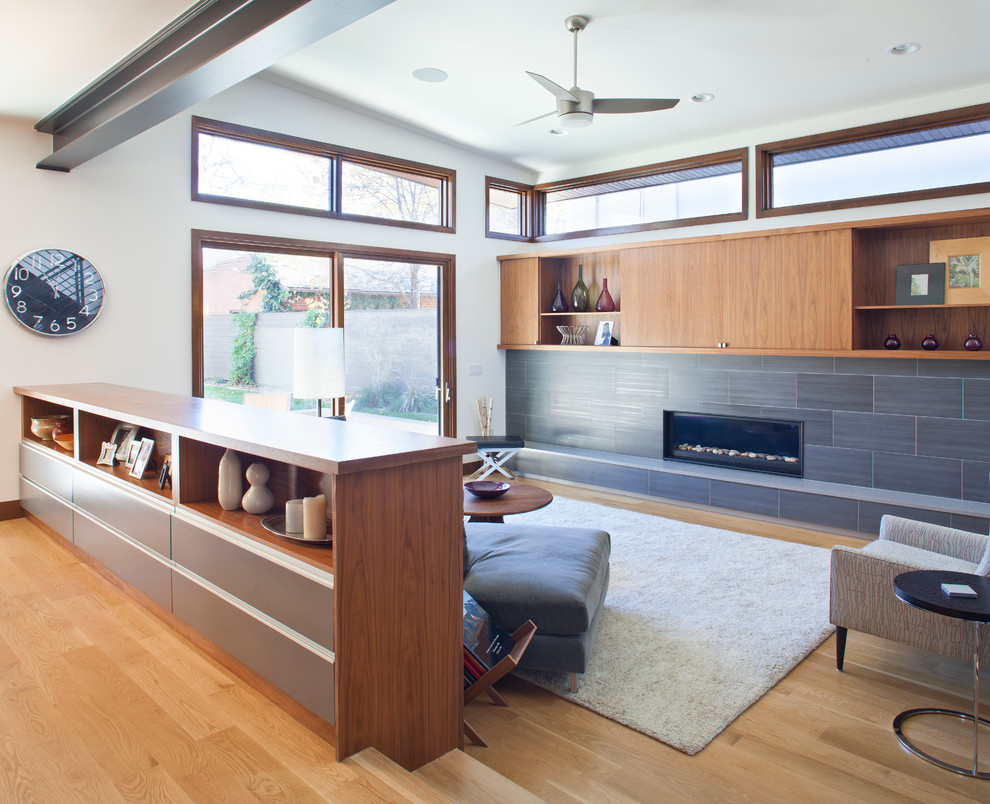 Offenes Modernes Wohnzimmer mit weißer Wandfarbe, braunem Holzboden, Gaskamin und gefliester Kaminumrandung in Denver