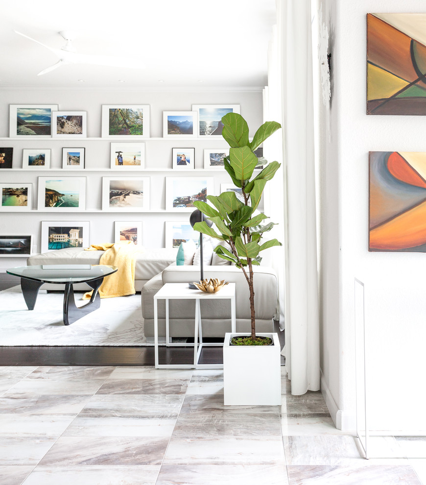 На фото: большая изолированная, парадная гостиная комната в стиле ретро с белыми стенами, стандартным камином, фасадом камина из металла, телевизором на стене, мраморным полом и серым полом с