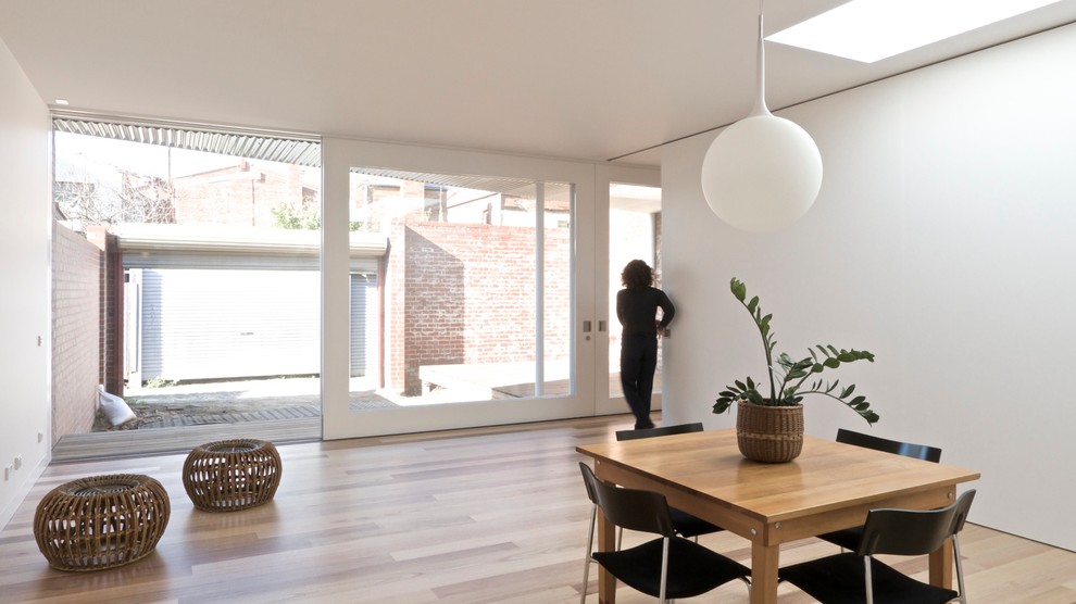 Cette photo montre un salon tendance ouvert avec un mur blanc et un sol en bois brun.