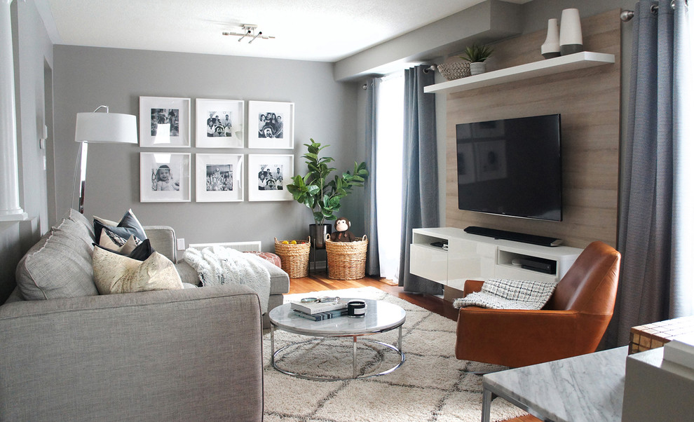 This is an example of a medium sized contemporary mezzanine living room in Toronto with grey walls, medium hardwood flooring, no fireplace and a wall mounted tv.