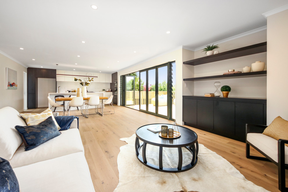 Medium sized modern formal open plan living room in Auckland with white walls, light hardwood flooring, no tv and beige floors.