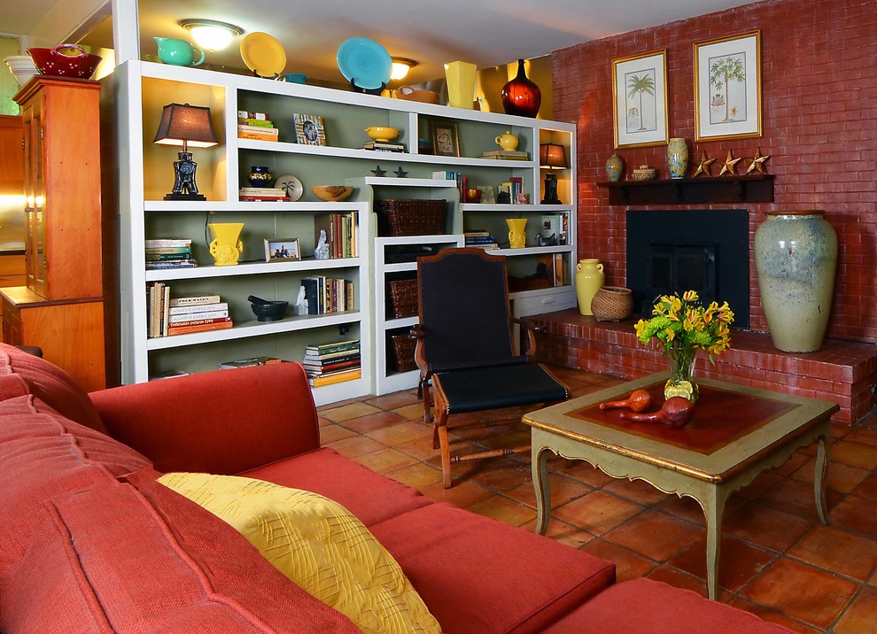 Esempio di un soggiorno tradizionale di medie dimensioni e aperto con libreria, pareti rosse, pavimento in terracotta, camino classico, cornice del camino in mattoni e nessuna TV