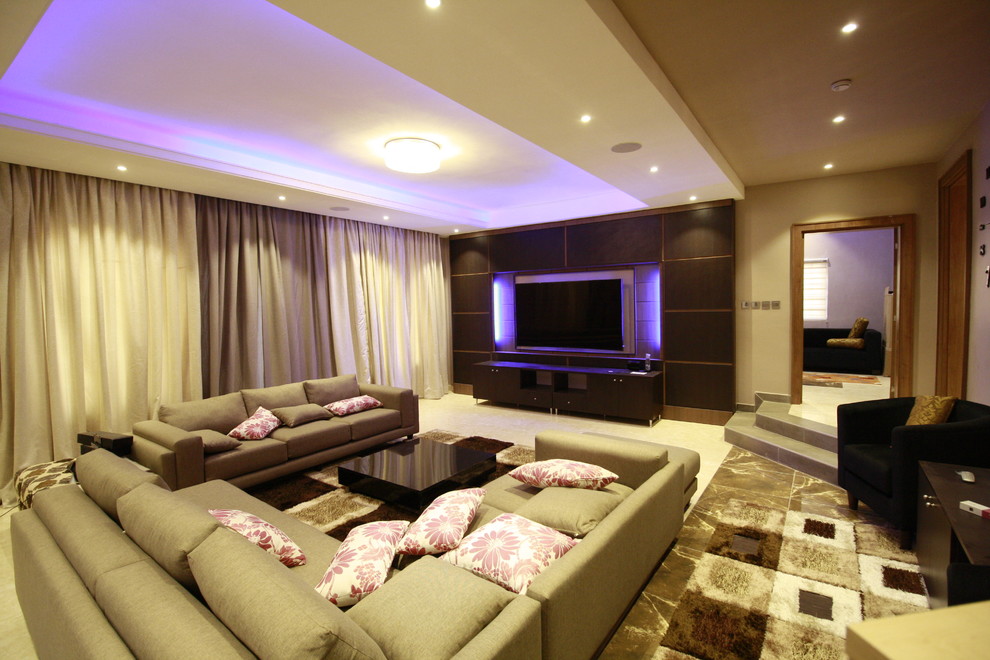 Ejemplo de salón abierto actual grande con paredes marrones, suelo de baldosas de cerámica y televisor colgado en la pared