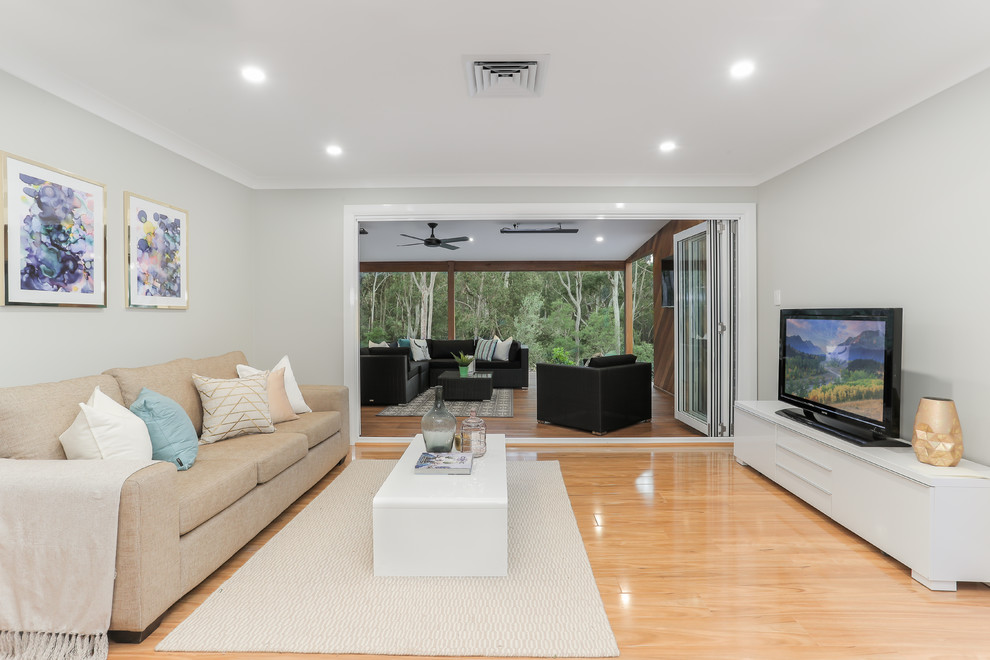 Medium sized contemporary enclosed living room in Sydney with grey walls, light hardwood flooring, a freestanding tv and yellow floors.