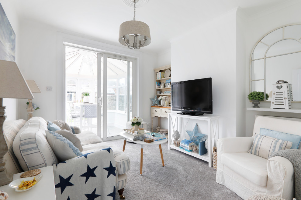 This is an example of a small beach style formal enclosed living room in Sussex with white walls, carpet, a freestanding tv and grey floors.