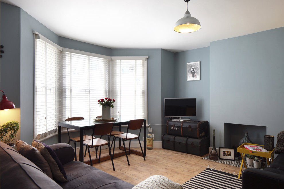 Exempel på ett litet skandinaviskt separat vardagsrum, med ett finrum, blå väggar, mellanmörkt trägolv, en standard öppen spis, en spiselkrans i gips och en fristående TV