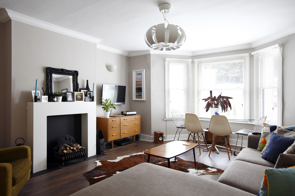 Inredning av ett minimalistiskt mellanstort separat vardagsrum, med ett finrum, grå väggar, laminatgolv, en öppen vedspis, en spiselkrans i gips och en väggmonterad TV