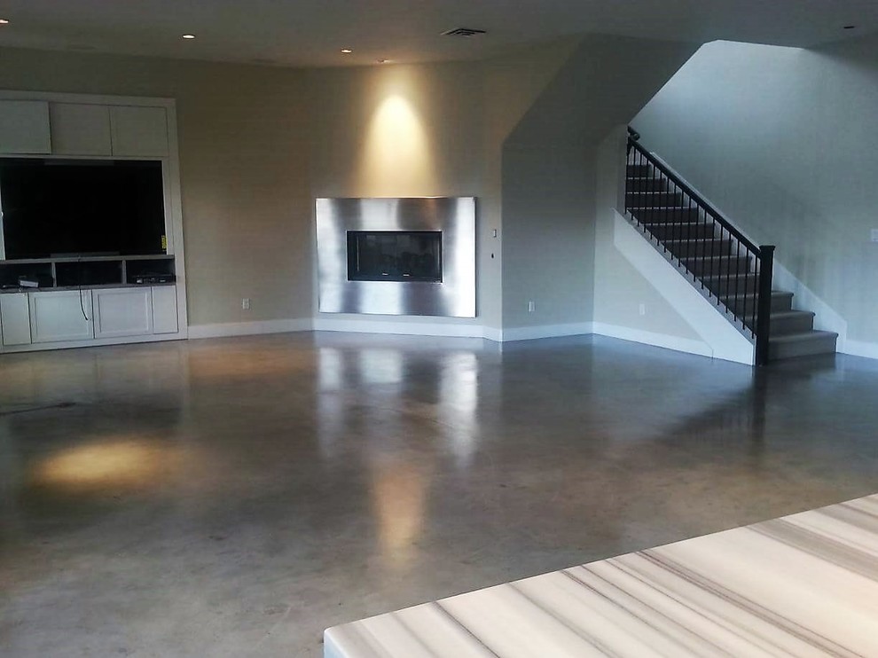 This is an example of a large contemporary open plan living room in Las Vegas with grey walls, concrete flooring, a standard fireplace, a metal fireplace surround, a built-in media unit and grey floors.