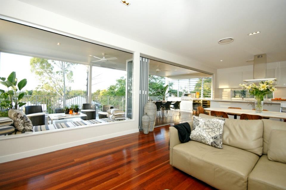 Offenes Klassisches Wohnzimmer ohne Kamin mit weißer Wandfarbe, braunem Holzboden und freistehendem TV in Brisbane