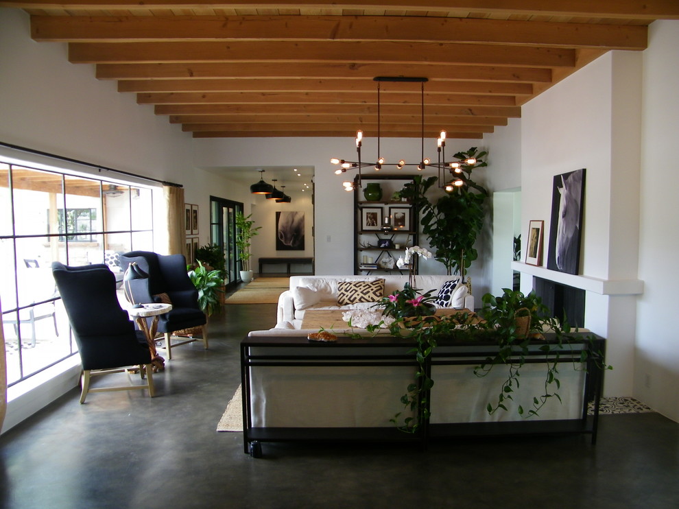 Пример оригинального дизайна: большая парадная, изолированная гостиная комната в классическом стиле с белыми стенами, бетонным полом, стандартным камином и фасадом камина из штукатурки без телевизора