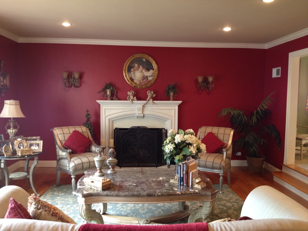 На фото: изолированная гостиная комната среднего размера в классическом стиле с красными стенами, паркетным полом среднего тона, стандартным камином и фасадом камина из штукатурки без телевизора с