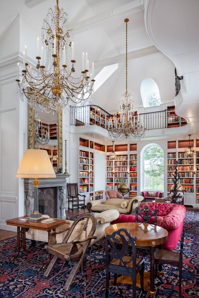 Cette image montre un salon traditionnel avec une bibliothèque ou un coin lecture, un mur blanc, un sol en bois brun, une cheminée standard et un sol marron.