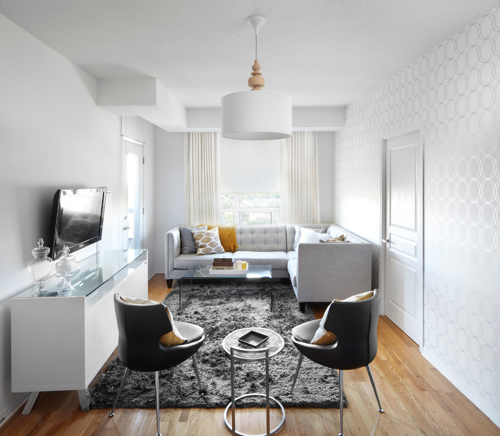 Example of a trendy medium tone wood floor living room design in Calgary with white walls and a wall-mounted tv