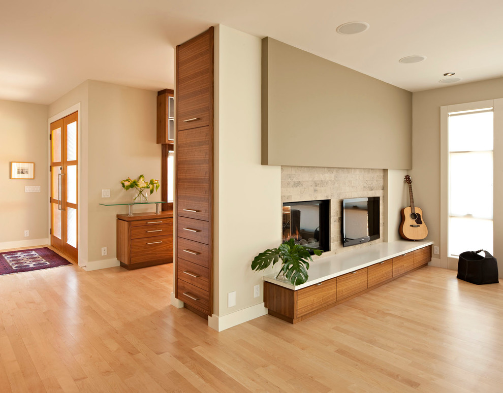 Minimalist light wood floor living room photo in Calgary with beige walls and a two-sided fireplace