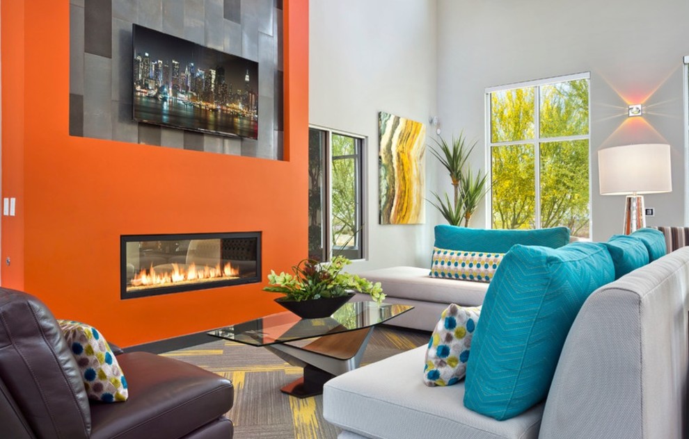 На фото: парадная, открытая гостиная комната среднего размера в современном стиле с оранжевыми стенами, ковровым покрытием, двусторонним камином, фасадом камина из штукатурки, телевизором на стене и серым полом с
