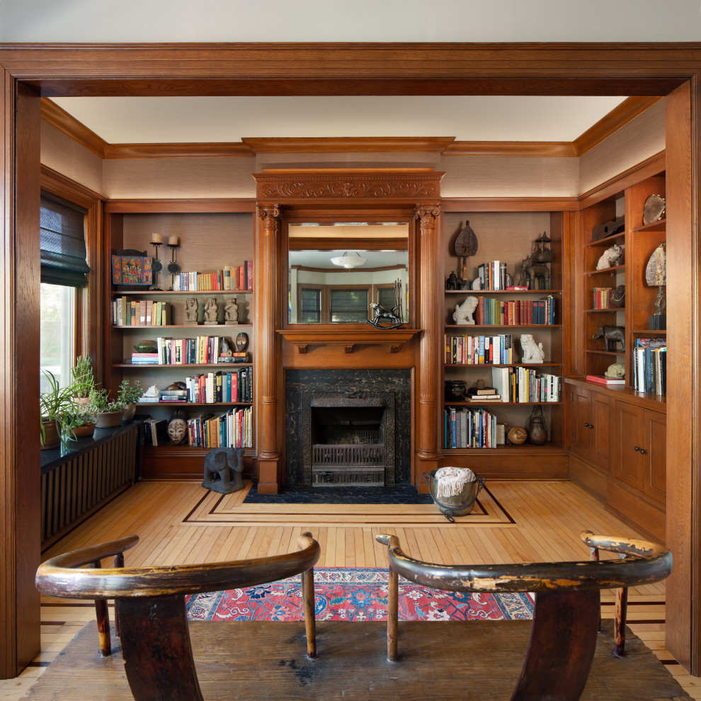 Immagine di un soggiorno etnico chiuso con libreria, pareti marroni, pavimento in legno massello medio, camino classico, pavimento marrone e carta da parati