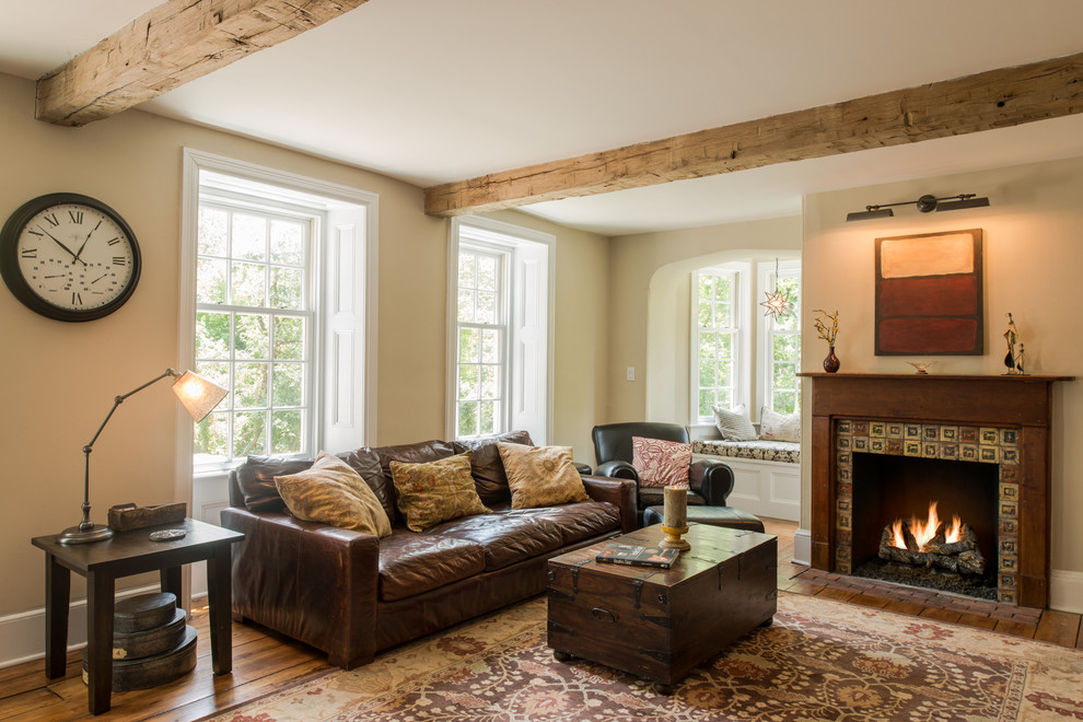 Idée de décoration pour un salon tradition fermé avec un manteau de cheminée en carrelage, un mur beige, un sol en bois brun, une cheminée standard, aucun téléviseur et éclairage.