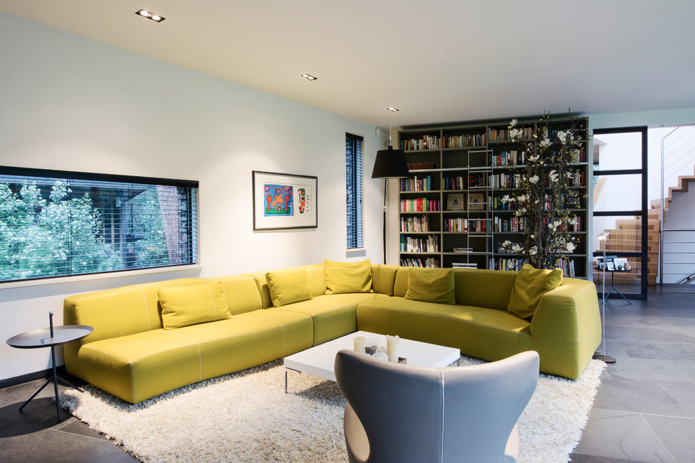 Immagine di un grande soggiorno design aperto con pareti bianche, pavimento con piastrelle in ceramica e TV nascosta