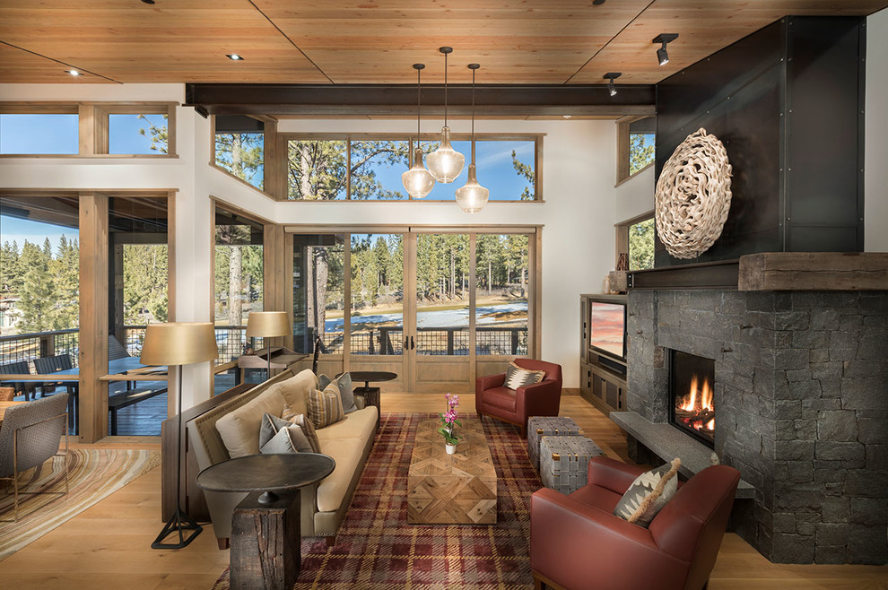 This is an example of a large rustic open plan living room in Other with a standard fireplace, a stone fireplace surround, white walls, a built-in media unit and light hardwood flooring.