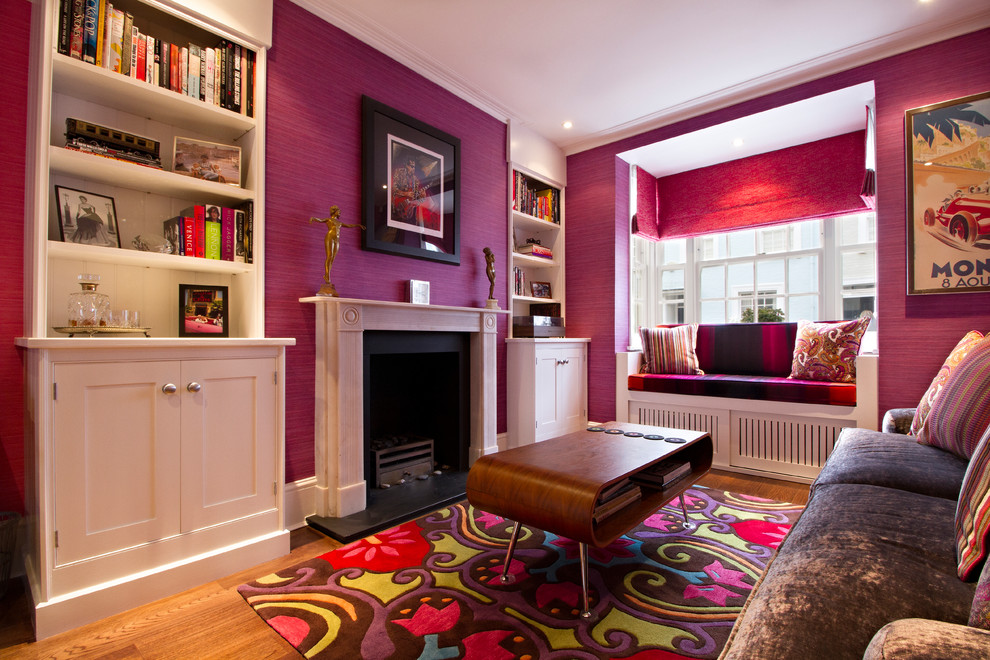 Photo of a medium sized modern enclosed living room in London with pink walls, medium hardwood flooring, a standard fireplace and a stone fireplace surround.