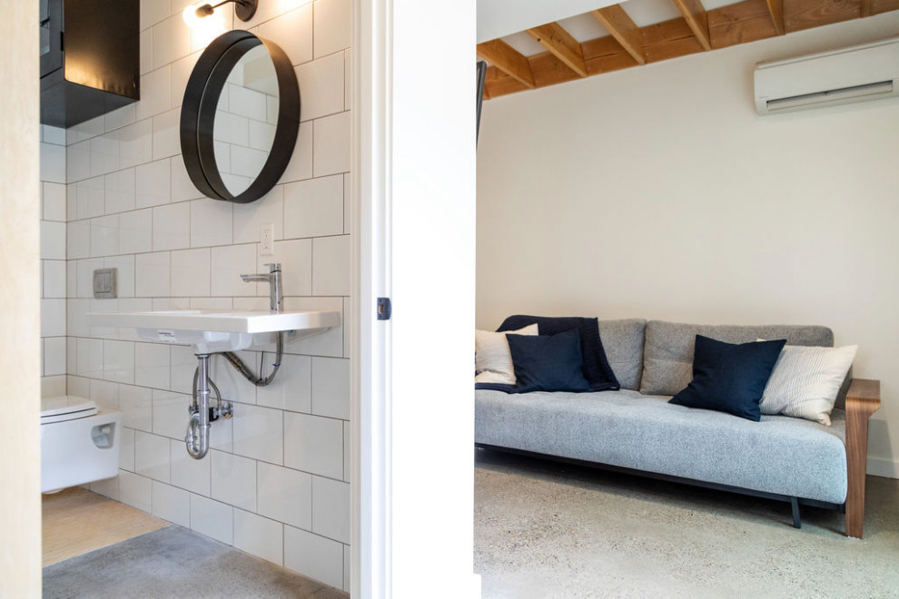 Foto di un piccolo soggiorno contemporaneo aperto con pareti bianche, pavimento in cemento, TV a parete e pavimento grigio